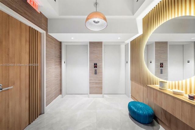 hall with elevator, light tile patterned floors, and wallpapered walls