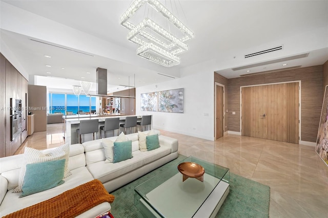 living area with baseboards, marble finish floor, and a notable chandelier