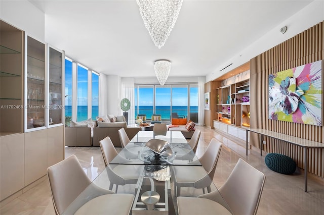 dining room with floor to ceiling windows, a water view, a healthy amount of sunlight, and a notable chandelier