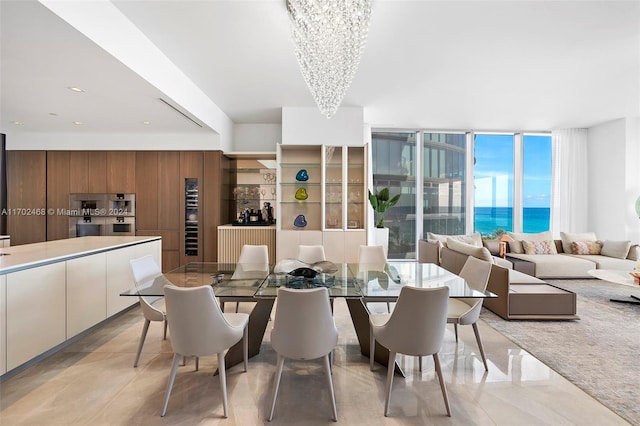 dining room featuring wooden walls, plenty of natural light, a water view, and a notable chandelier