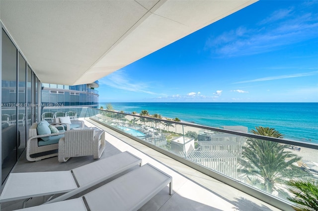 balcony with an outdoor hangout area, a water view, and a view of the beach