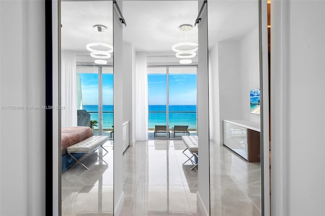 hallway with a water view, an inviting chandelier, and expansive windows