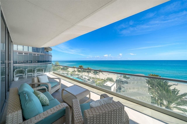 balcony featuring an outdoor living space, a water view, and a beach view