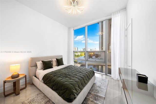 bedroom featuring an inviting chandelier, expansive windows, light tile patterned floors, and a view of city