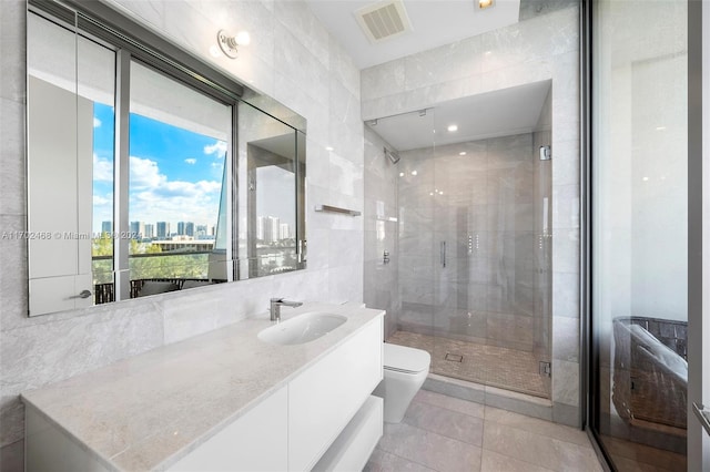 bathroom featuring tile patterned floors, an enclosed shower, vanity, tile walls, and toilet