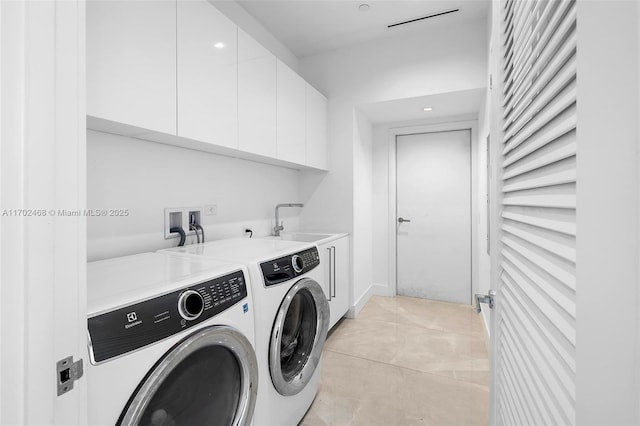 washroom featuring washing machine and dryer, cabinet space, a sink, and light tile patterned flooring