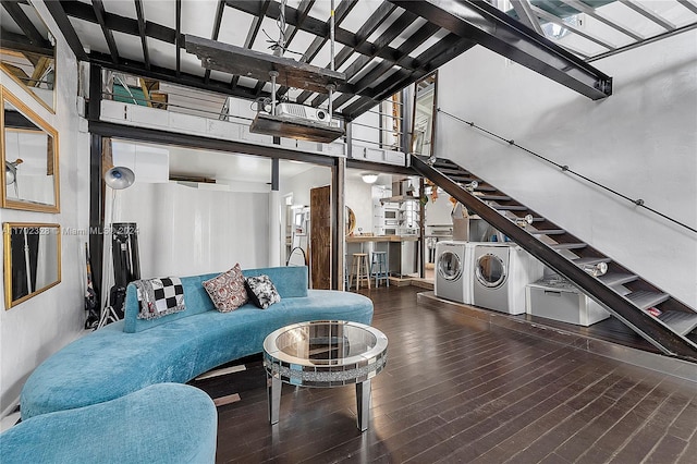 living room with hardwood / wood-style floors, a towering ceiling, and separate washer and dryer