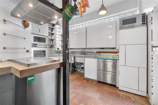 kitchen featuring island exhaust hood, white cabinets, decorative light fixtures, and appliances with stainless steel finishes