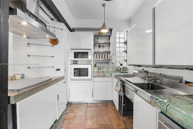 kitchen with pendant lighting, white cabinets, wall chimney range hood, and white oven