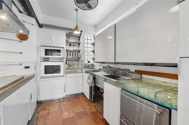 kitchen featuring white cabinets, white appliances, hanging light fixtures, and wall chimney range hood