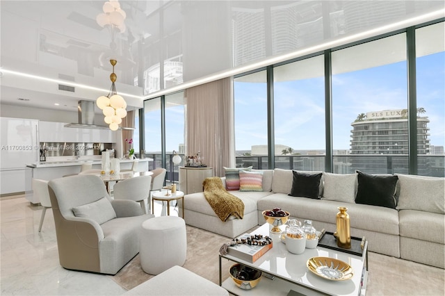 living room featuring an inviting chandelier, a towering ceiling, and floor to ceiling windows