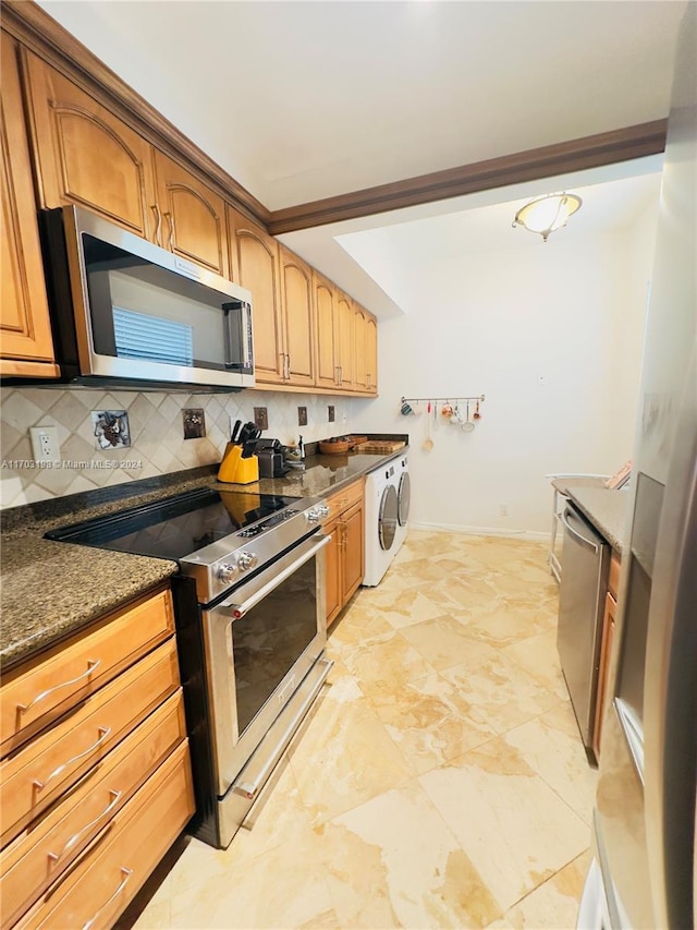 kitchen featuring decorative backsplash, washer and dryer, dark stone countertops, and stainless steel appliances