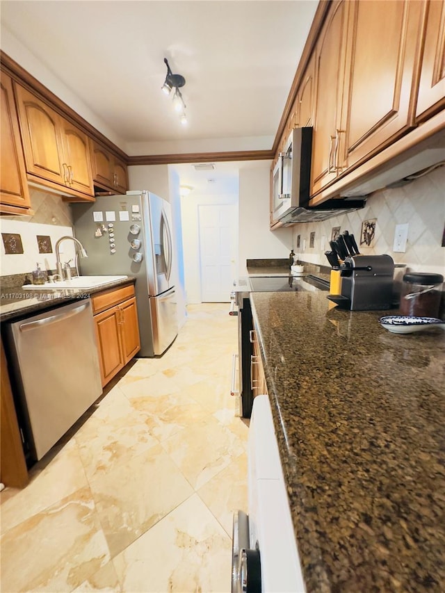 kitchen featuring rail lighting, sink, dark stone countertops, appliances with stainless steel finishes, and tasteful backsplash