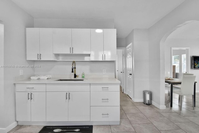 kitchen with white cabinets, light tile patterned floors, and sink