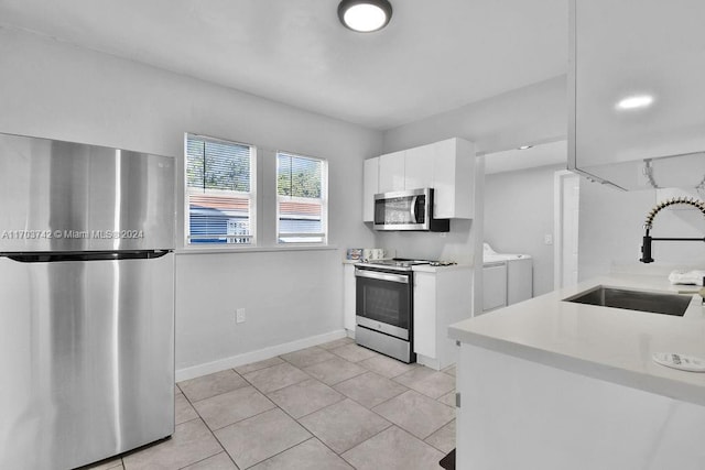 kitchen featuring white cabinets, sink, separate washer and dryer, light tile patterned floors, and stainless steel appliances