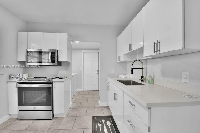 kitchen with white cabinets, light tile patterned flooring, sink, and appliances with stainless steel finishes