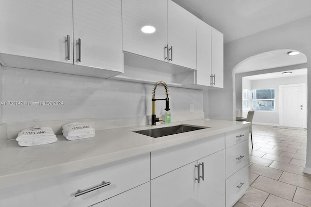 kitchen featuring white cabinets, light tile patterned floors, and sink