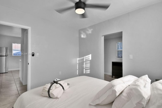 bedroom featuring stainless steel fridge, light tile patterned floors, and ceiling fan