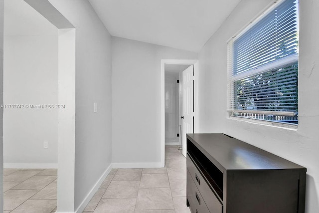 hallway featuring lofted ceiling and light tile patterned floors