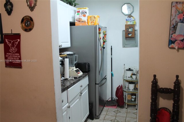 677 SW 9th Ave Unit 103, Miami, FL 33130 - kitchen featuring white cabinets, dark countertops, freestanding refrigerator, and light tile patterned floors