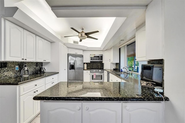 kitchen featuring white cabinetry, a raised ceiling, kitchen peninsula, and appliances with stainless steel finishes