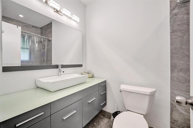 bathroom with tiled shower, vanity, and toilet