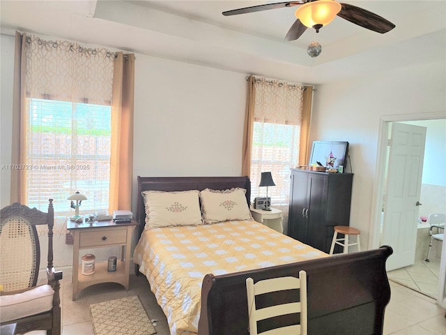 tiled bedroom with ceiling fan, a raised ceiling, and connected bathroom