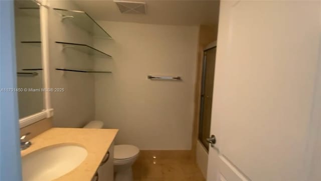 bathroom with bath / shower combo with glass door, visible vents, toilet, vanity, and baseboards