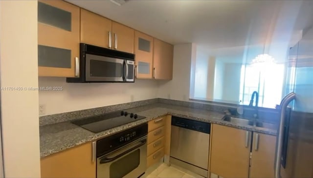 kitchen featuring appliances with stainless steel finishes, dark stone counters, glass insert cabinets, and a sink