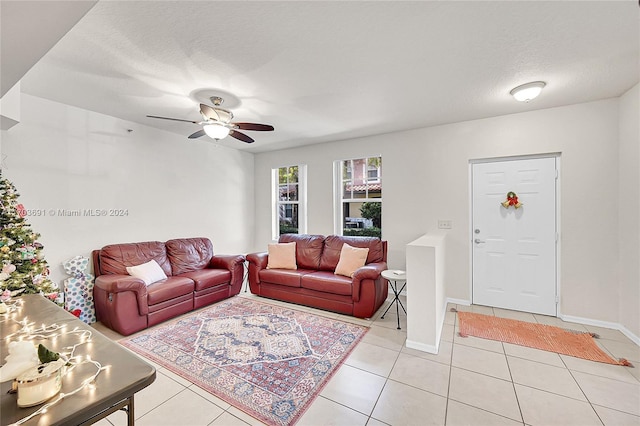 living room with ceiling fan, light tile patterned floors, and a textured ceiling