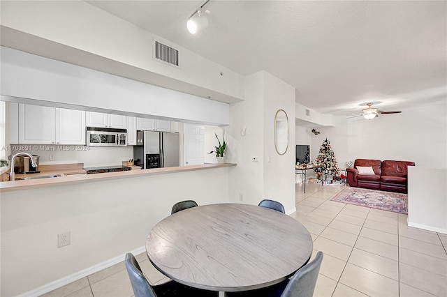 tiled dining space featuring rail lighting, ceiling fan, and sink