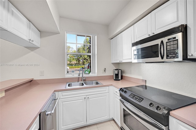 kitchen featuring appliances with stainless steel finishes, light tile patterned floors, white cabinetry, and sink