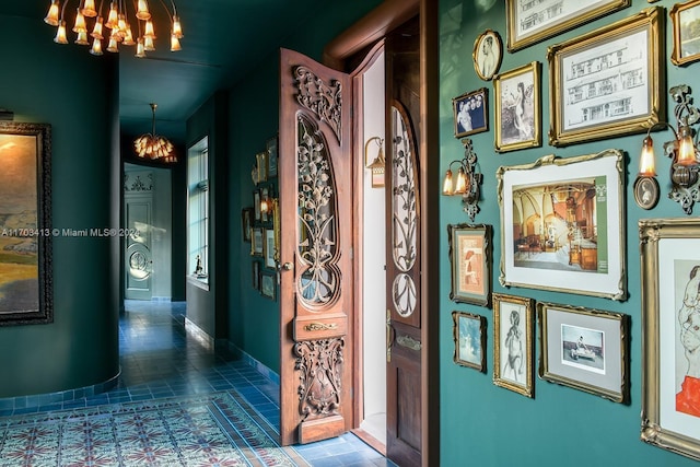 hall with a notable chandelier and dark tile patterned floors