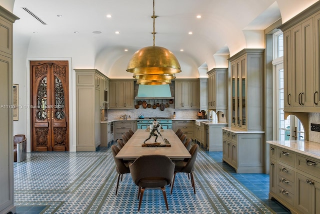 kitchen with a center island with sink, high end stainless steel range oven, pendant lighting, and vaulted ceiling