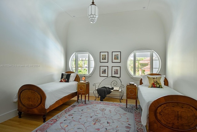 bedroom with high vaulted ceiling, light hardwood / wood-style flooring, and multiple windows