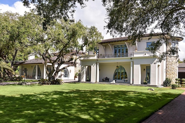 back of house with a lawn and a balcony