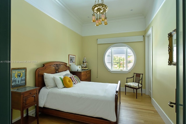 bedroom featuring light wood-type flooring, crown molding, and an inviting chandelier