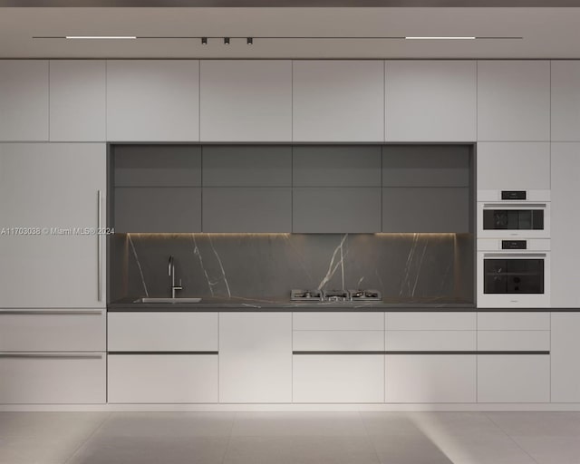 interior space with light tile patterned floors, tasteful backsplash, and sink