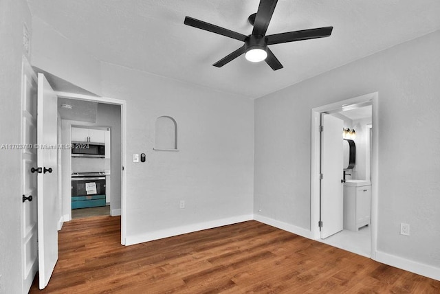 unfurnished bedroom with wood-type flooring, connected bathroom, and ceiling fan