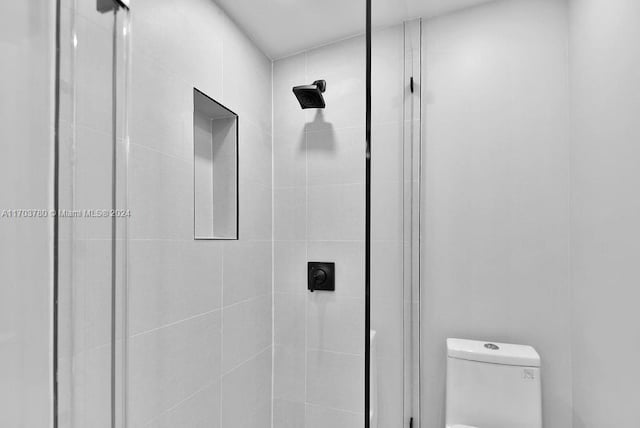 bathroom featuring toilet and a tile shower