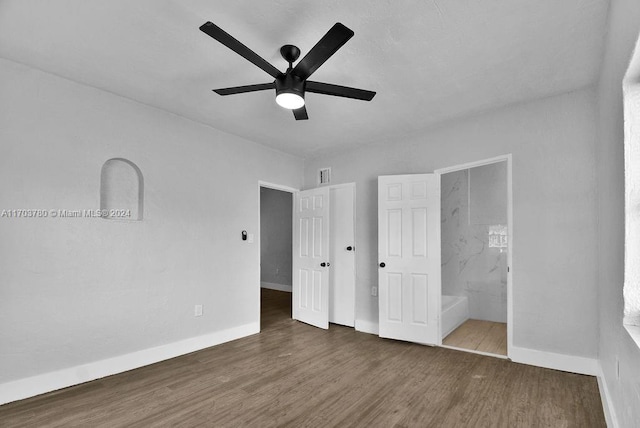 unfurnished bedroom featuring ceiling fan, dark wood-type flooring, and ensuite bath