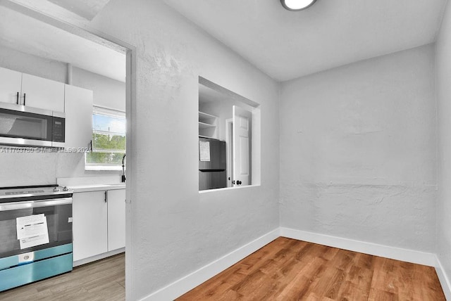 kitchen featuring white cabinets, light hardwood / wood-style floors, and stainless steel appliances