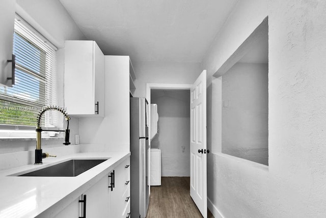 kitchen featuring stainless steel fridge, light hardwood / wood-style floors, white cabinetry, and sink