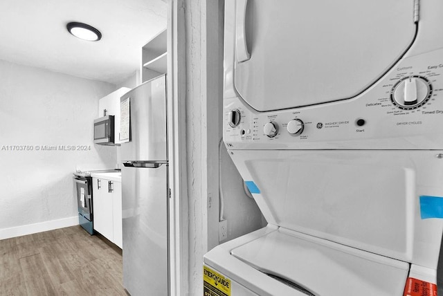 laundry area featuring stacked washer / dryer and light hardwood / wood-style floors