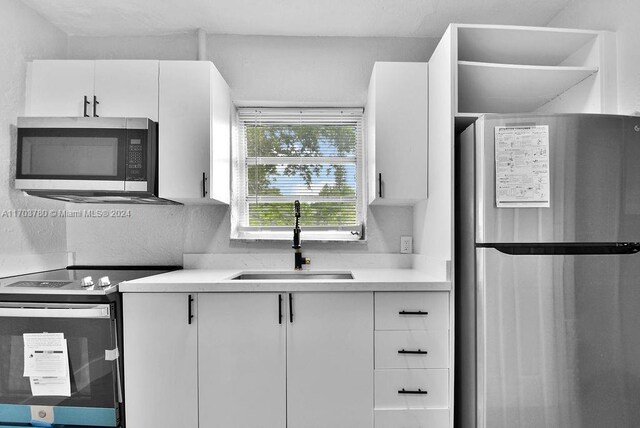 kitchen with appliances with stainless steel finishes, white cabinetry, and sink