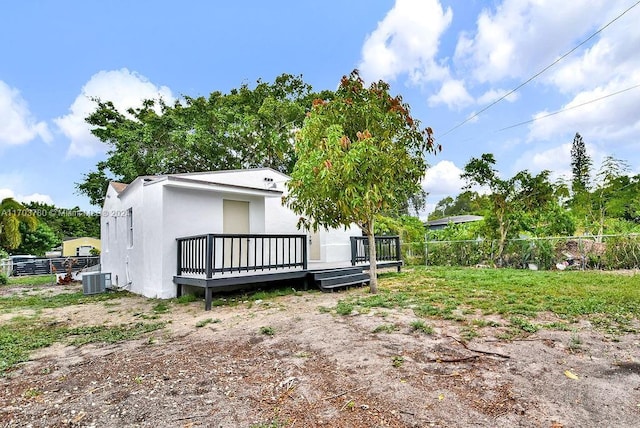 rear view of property featuring cooling unit and a wooden deck