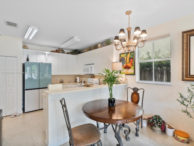 kitchen featuring kitchen peninsula, white appliances, decorative light fixtures, white cabinets, and a chandelier