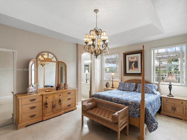 bedroom with ensuite bathroom, multiple windows, a notable chandelier, and a tray ceiling