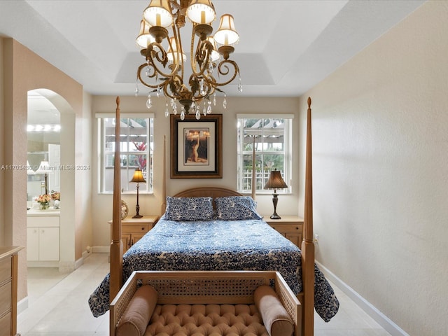 tiled bedroom with a raised ceiling, ensuite bathroom, and a notable chandelier