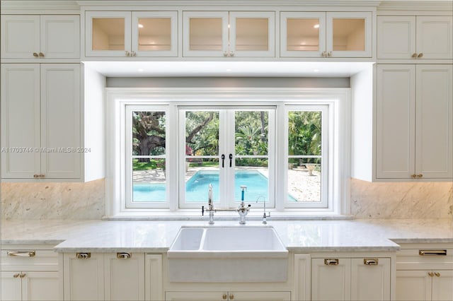 kitchen featuring white cabinetry, light stone countertops, and sink